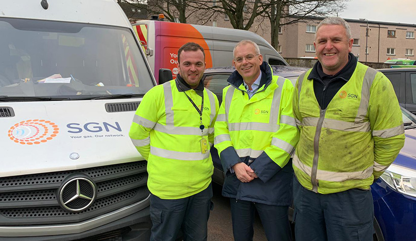 Three SGN colleagues wearing PPE and standing in front of an SGN van