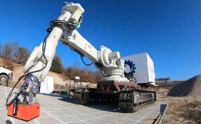 Our RRES prototype outside on a concrete surface. The prototype vehicle has continuous track 'wheels' and a large robotic arm. 