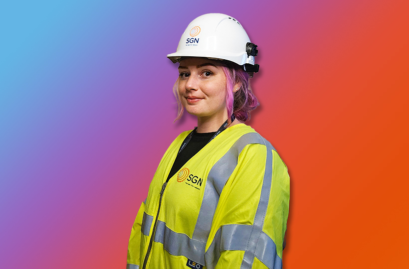 A young woman in SGN branded PPE in front of a blue to orange gradient