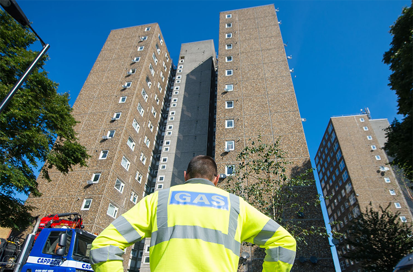 Gas engineer standing in front of high rise flat 