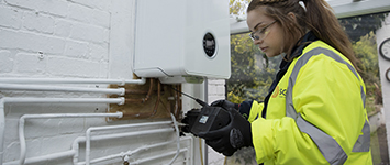image showing female SGN engineer checking a boiler in a customers home