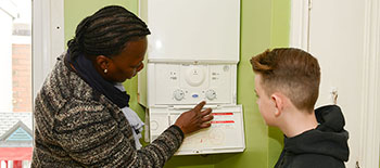 a woman and a young boy look at a boiler