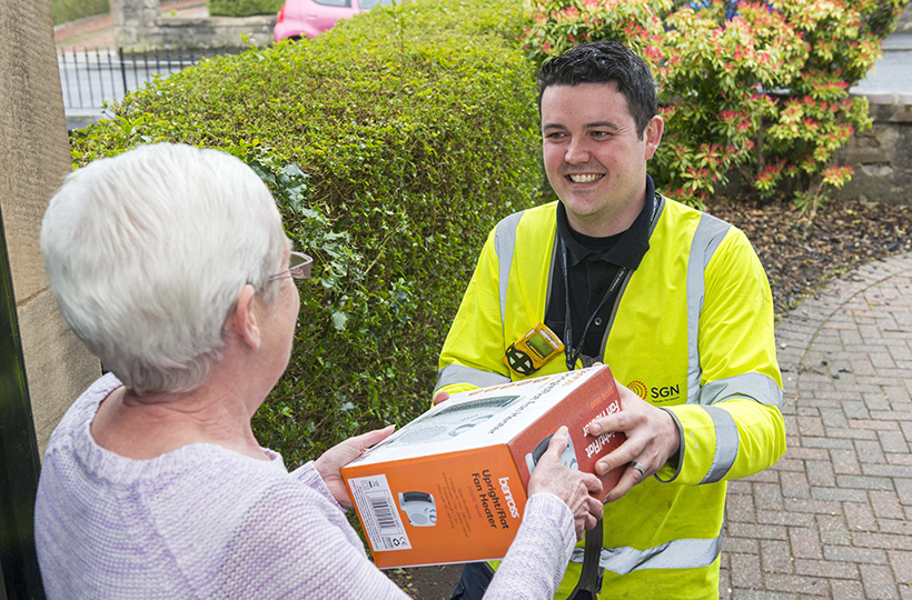 male SGN engineer handing a heater to a customer from the Priority Services Register