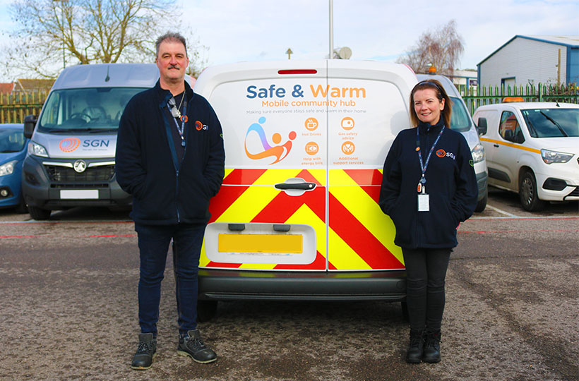 A man and woman in PPE stood in front of a Safe & Warm van