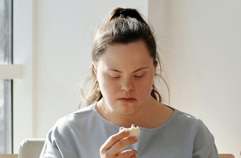 A young woman with down’s syndrome eating a biscuit 