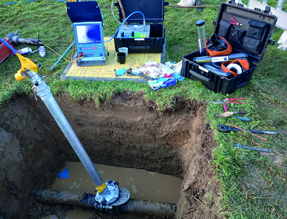 A hole dug in a lawn with a long metal piece of kit, also known as a stent, resting in it