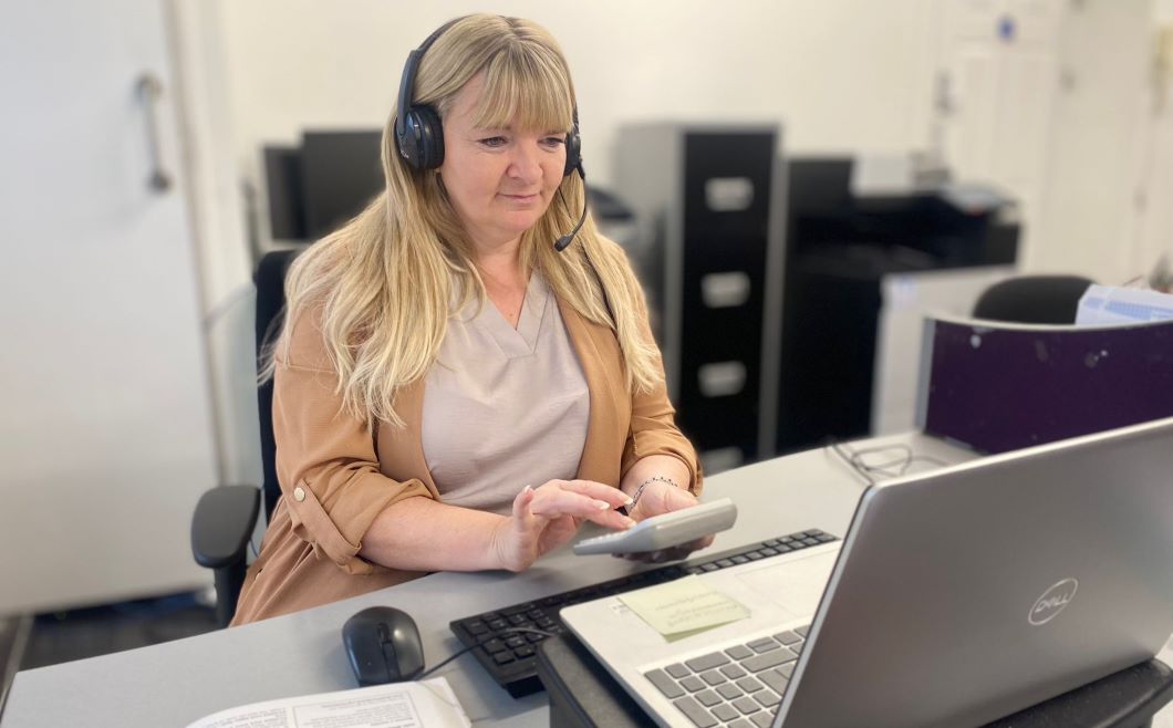 An IncomeMax adviser is sitting in front of her laptop with a calculator in her hand