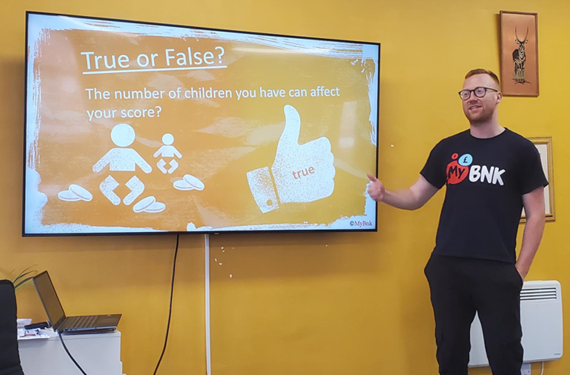 A man in a MyBnk tshirt in fron of a screen highlighting training for young people