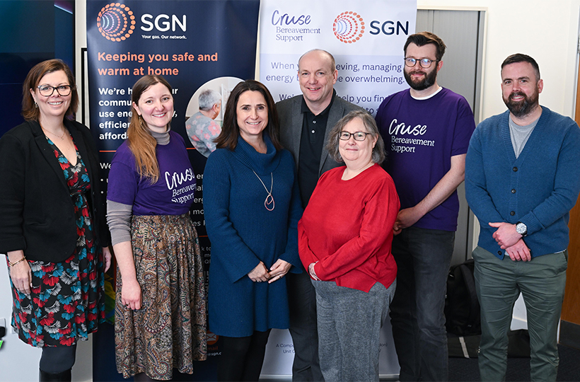 Seven smiling people in front of pop up banners for Cruse and SGN