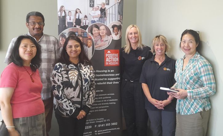 A group of SGN and charity representatives area standing in front of a Positive Action in Housing banner