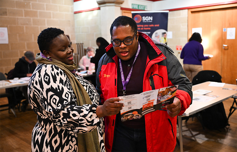 Two people in a community centre looking at a leflet about the Priority Services Register