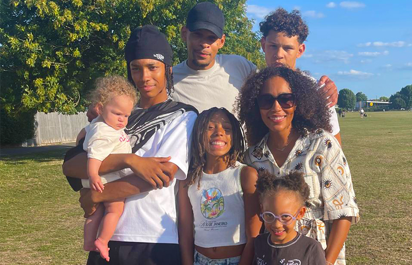 A Black man and woman with their five children in a sunny park