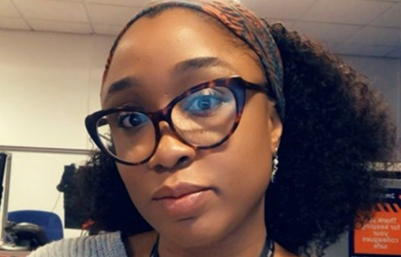 A Black woman with curly hair and glasses