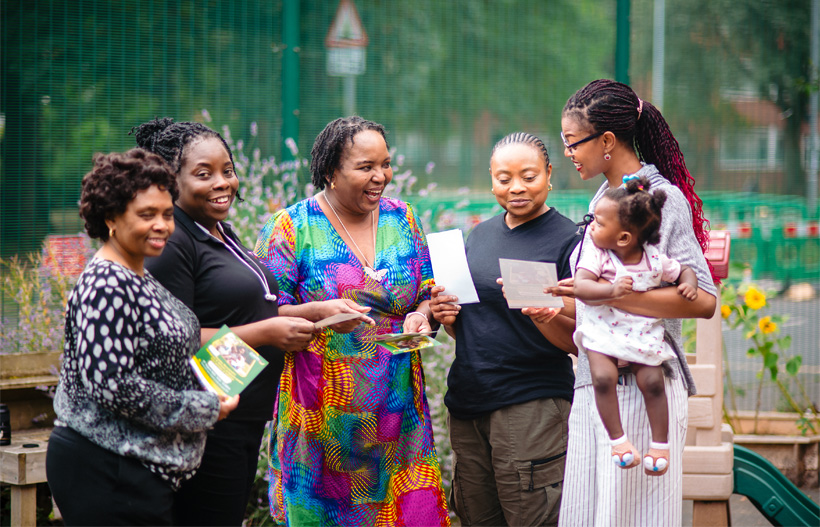 A group of smiling Black women looking at leaflets