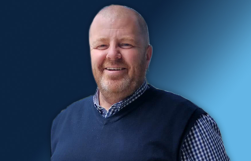 A smiling man in front of a blue gradient