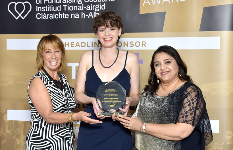 Three women holding a glass award