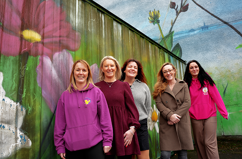 Five people standing in front of a colourful container