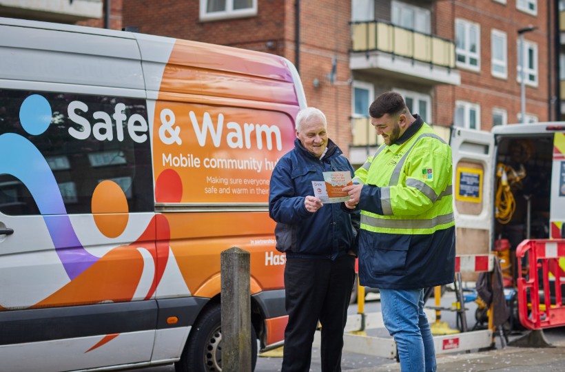 Image showing and SGN Safe and Warm van in the background with a member of SGN staff in hi vi clothing showing leaflets to an older customer