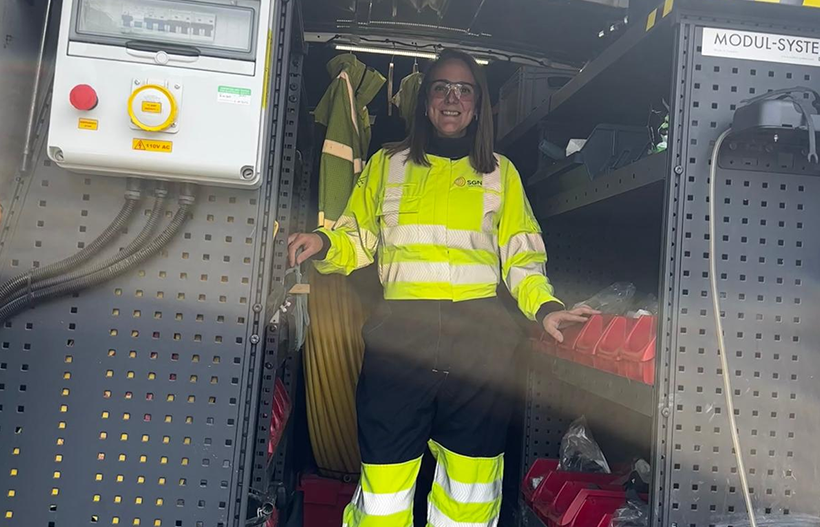 A smiling woman in PPE stood in the back of her van