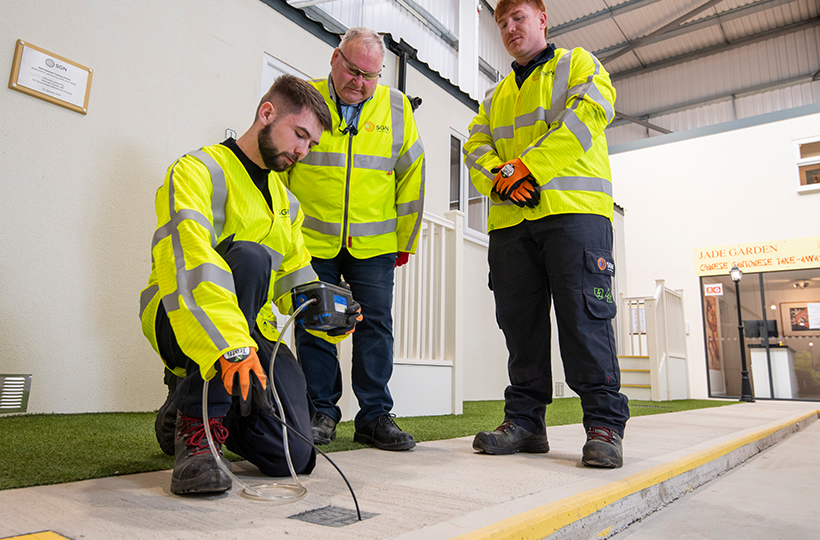Two young male apprentices being directed by their tutor in a training centre.