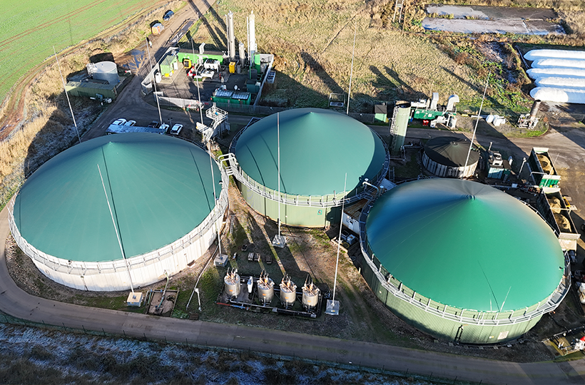 An aerial view of three large silos on a biomethane plant in the countryside.