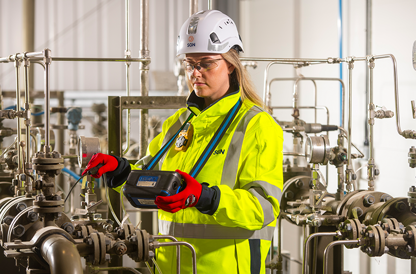 A female engineer in full PPE working on a gas system.