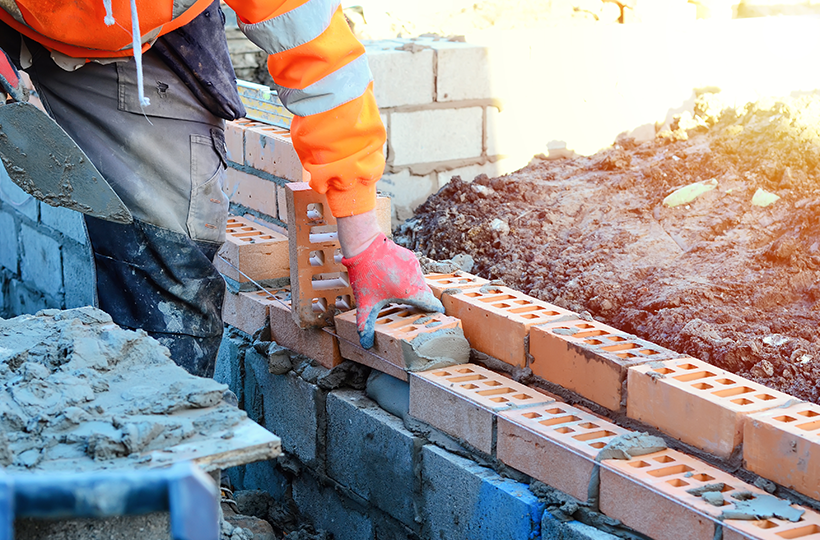 A builder laying bricks in a new wall.
