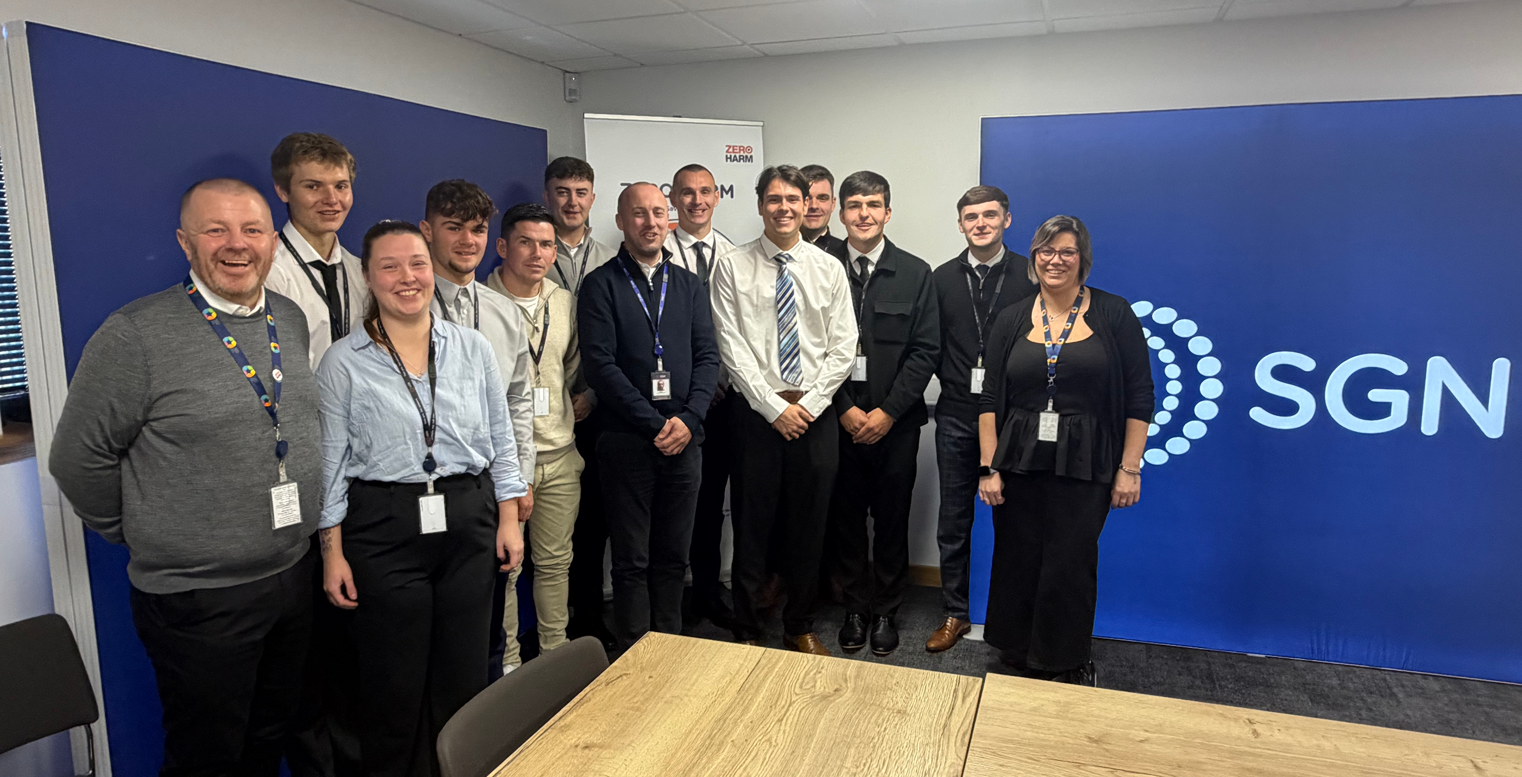 A group of smiling people in a classroom with an SGN banner in the background