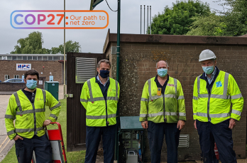 Four men wearing PPE and face masks standing in front of a gas governor station. Picture is captioned: COP27: Our path to net zero 