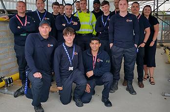 A group of 14 new apprentices standing in rows at East Sussex College where there is a specialist gas industry training facillity