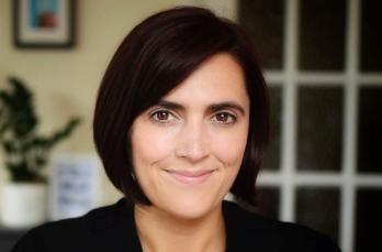 Head and shoulders image of woman in smart clothing and domestic property setting behind her.