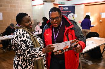 Two people in a community centre looking at a leflet about the Priority Services Register