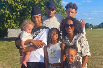 A Black man and woman with their five children in a sunny park
