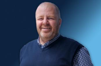 A smiling man in front of a blue gradient