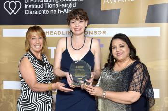 Three women holding a glass award
