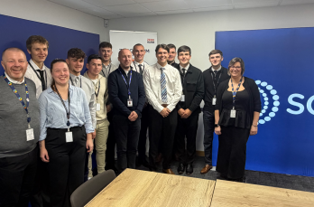 A group of smiling people in a classroom with an SGN banner in the background